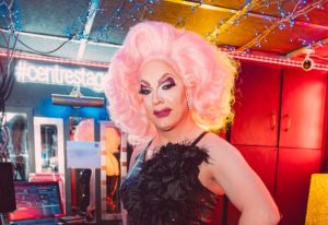 Drag queen at Centre Stage, Manchester. Pink wig, sequin dress, and feather boa. Gay travel advice, LGBTQ+ nightlife.