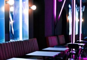 Euforia Bar Milan interior. Chic gay bar with neon lights, plush seating, and modern tables. A trendy spot for gay men's travel in Milan.