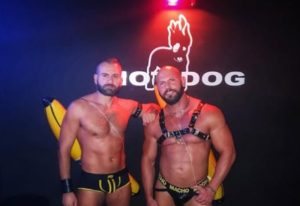 Two muscular men pose at Hot Dog Club Milan. One wears a harness, the other briefs. Gay travel hotspot. Nightlife.