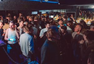 New York New York Manchester: Crowd of gay men at a bar. Gay travel advice for nightlife. Men socializing, drinking, and enjoying the atmosphere.