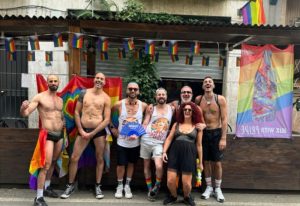 Gay group at NoLoSo Bar, Milan. Rainbow flags, shirtless men, and vibrant energy capture the gay travel scene in Milan, Italy.