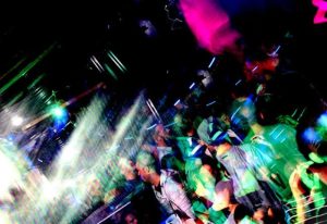 QClub Milan gay party scene. Blurry image of a crowded dance floor with colorful lights. Gay nightlife in Milan, Italy. Men dancing.