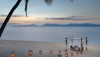 Santiburi Koh Samui private dinner on Maenam beach. Romantic beachfront dining setup with lanterns at dusk. Gay travel advice.