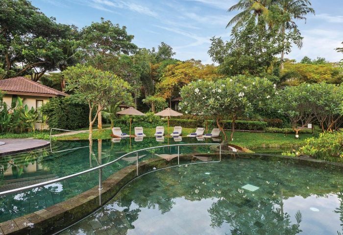 SAii Koh Samui Villas pool view. Lush tropical landscape with sun loungers. Perfect for gay men's travel, offering relaxation and luxury.