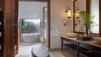 Santiburi Koh Samui deluxe beachfront villa bathroom. Bathtub, double vanity with vessel sinks, and tropical decor. Gay travel luxury resort.