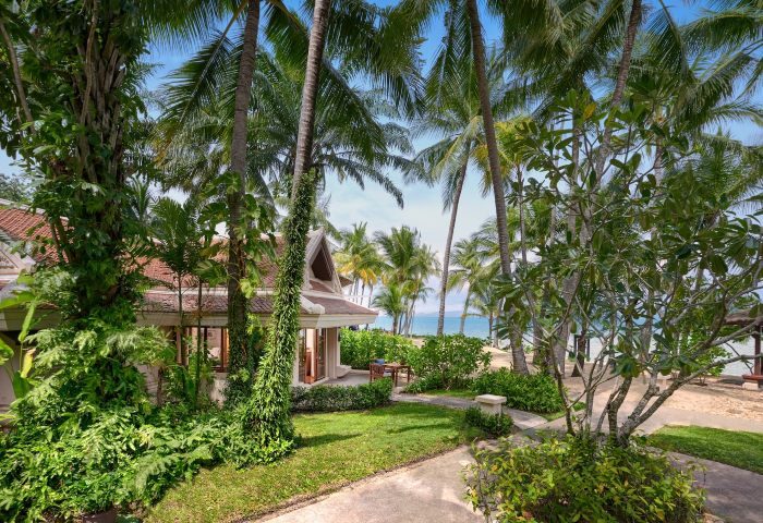 Santiburi Koh Samui deluxe beachfront villa exterior. Tropical gay travel destination with palm trees, beach, and luxurious villa.