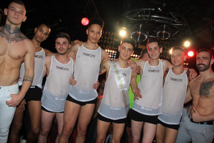 Universe Jeunes: Group of gay men at a party, one wearing a Mister Universe Jeunes Paris sash. Nightlife, travel, and gay community.