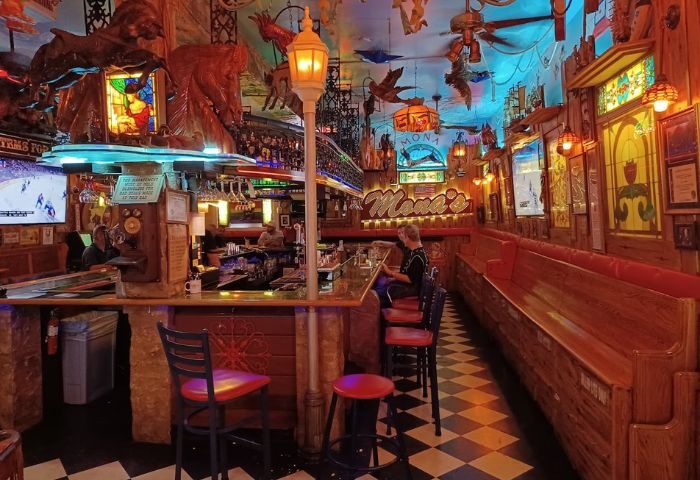 Interior of Mona's Cocktail Lounge, a gay bar. Ornate decor, bar seating, and cozy booths. A unique travel destination for gay men.