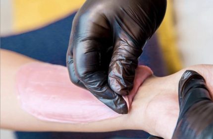 AlexSpot24: Man's arm being waxed. Pink wax is applied by hands in black gloves. Gay travel advice: grooming tips for smooth skin.