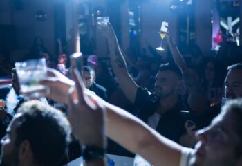 Gay men raising glasses at R House, a vibrant gay bar. Nightlife scene with drinks, music, and a celebratory atmosphere. 1-24.jpg