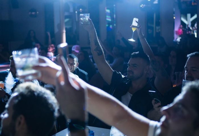 Gay men raising glasses at R House, a vibrant gay bar. Nightlife scene with drinks, music, and a celebratory atmosphere. 1-24.jpg