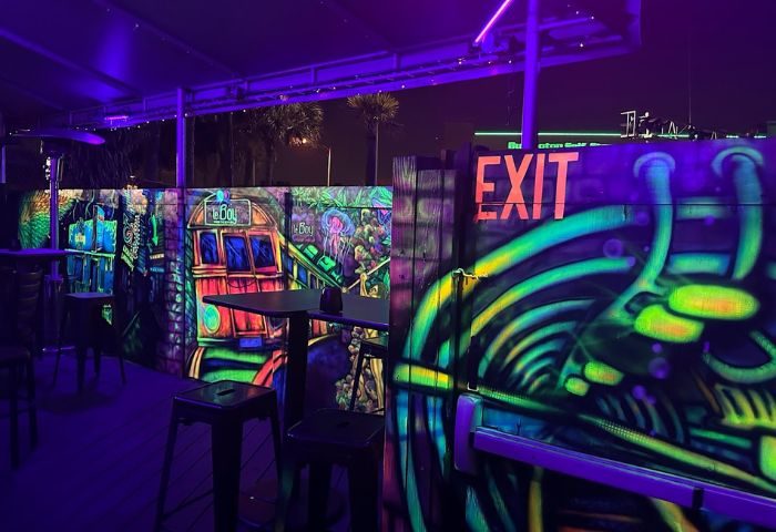 LeBoy gay bar patio at night. Neon graffiti art, tables, chairs, and exit sign. Gay travel destination. Nightlife scene. 1-4.jpg