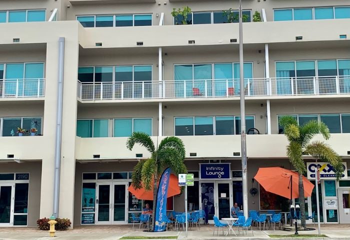 Infinity Lounge, gay travel advice: Exterior view of the lounge with outdoor seating, palm trees, and modern architecture. Gay bar.