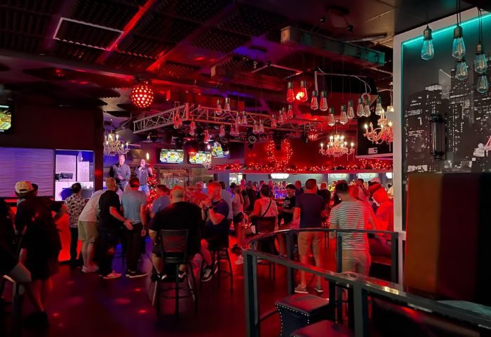 Interior of Georgie's ALIBI Monkey Bar, a gay bar. Men gather under red lights and chandeliers. Stage with performers. 1-8.jpg