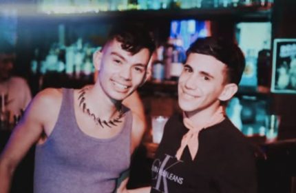 Two gay men smiling at 101 Club Roma. Nightlife scene with bar background. Gay travel advice, gay bar, Roma nightlife.