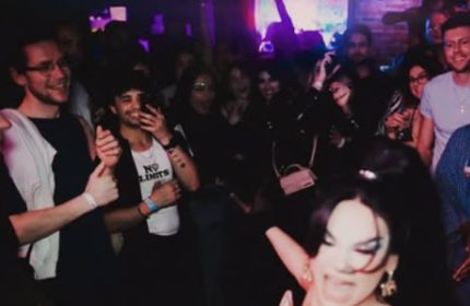 Inside 101 Club Roma, a crowded gay club. People are dancing, smiling, and enjoying the vibrant atmosphere. Gay travel advice.