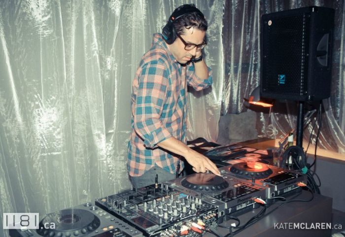 Vancouver gay nightlife: DJ at 1181 Lounge, a popular gay bar. Man with headphones mixes music. Travel advice for gay men.