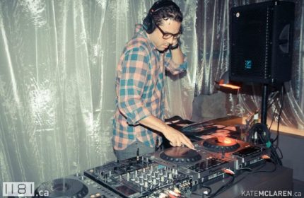 Vancouver gay nightlife: DJ at 1181 Lounge, a popular gay bar. Man with headphones mixes music. Travel advice for gay men.