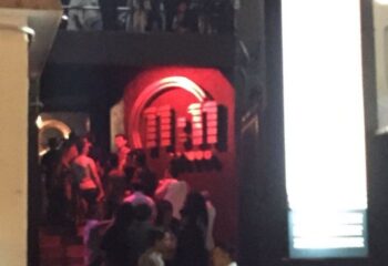 Entrance to 11:11 Club, a gay bar in Cancun, Mexico. People are gathered near the entrance. Red lighting highlights the club's logo.