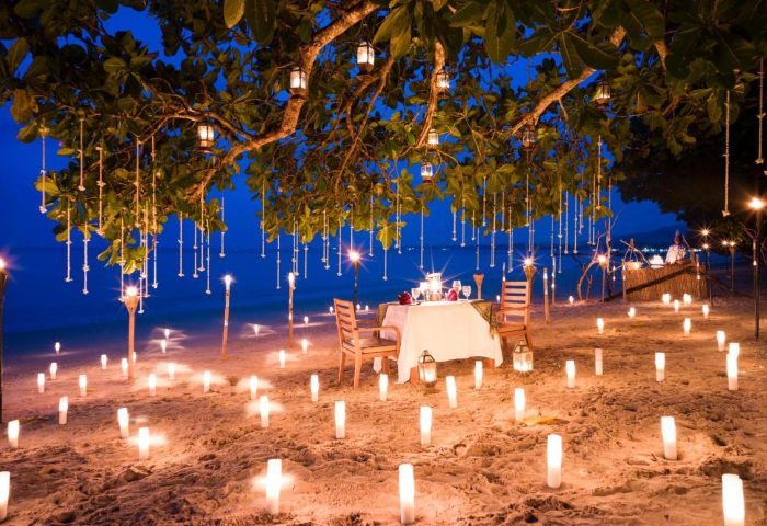 Romantic beach dinner at The Sarojin Khao Lak. Candles light the sand path to a table for two under a tree with lanterns. 18350002.jpg