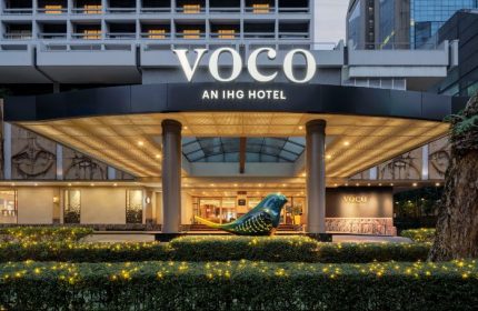 Entrance of voco Orchard Singapore, an IHG Hotel. Bird sculpture, bright lights, and modern architecture. A gay-friendly hotel in Singapore.