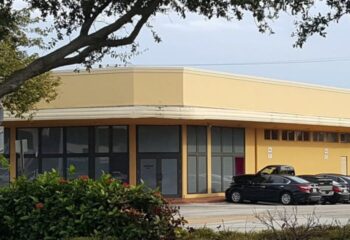 The Clubhouse II: A yellow commercial building with dark-tinted windows. Cars are parked in front. Gay men's travel advice. 2-14.jpg