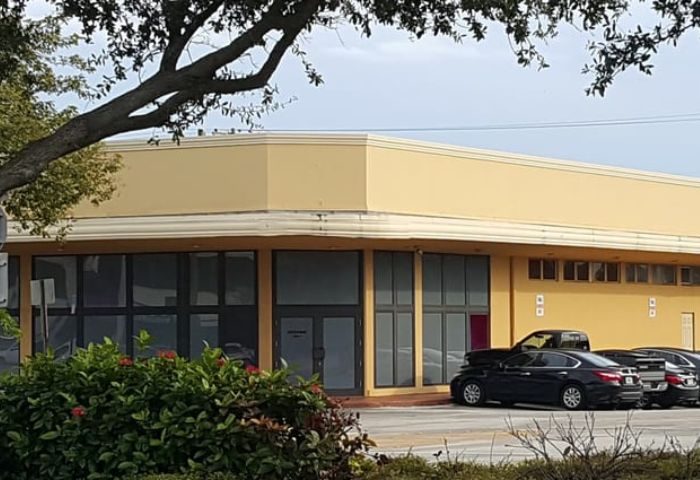 The Clubhouse II: A yellow commercial building with dark-tinted windows. Cars are parked in front. Gay men's travel advice. 2-14.jpg