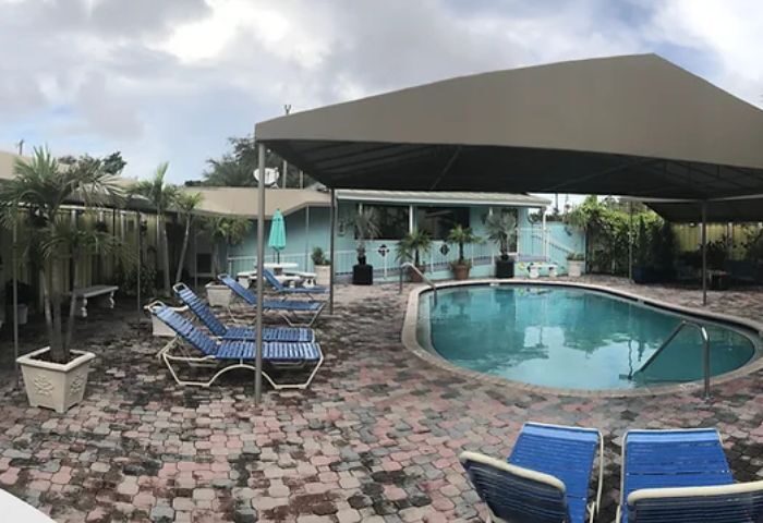 Club Aqua pool view. Gay-friendly travel destination with blue lounge chairs, palm trees, and a covered pool area. 2-17.jpg.