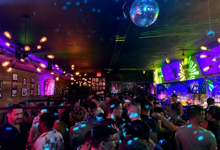 Inside Nathan's Beach Club: A crowded gay bar with disco balls, colorful lights, and a lively atmosphere. Nightlife for gay men travel.