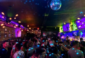 Inside Nathan's Beach Club: A crowded gay bar with disco balls, colorful lights, and a lively atmosphere. Nightlife for gay men travel.