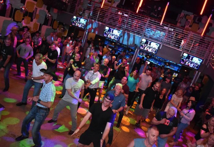 Hunters Wilton Manors: A packed gay bar dance floor with men dancing under colorful lights. Nightlife scene, gay travel advice.