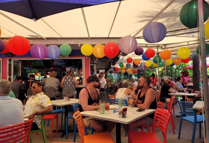 Patio at Rosie's Bar & Grill, gay bar. Colorful lanterns hang above patrons at tables and the bar. Gay travel destination.