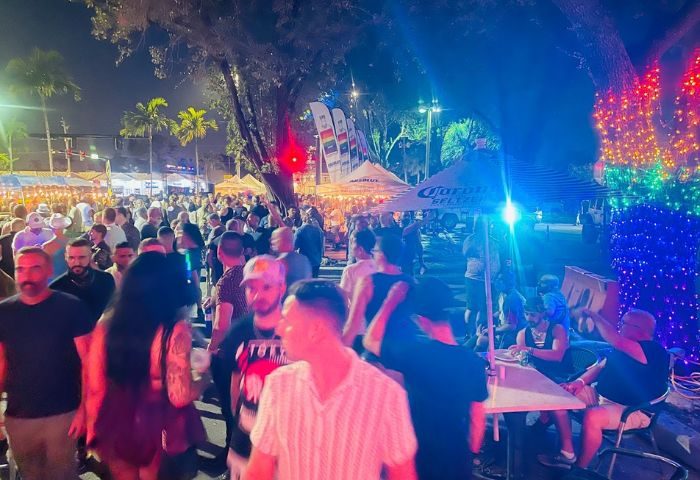 Georgie's ALIBI Monkey Bar: Night scene of a crowded outdoor gay bar. Men gather under tents and lights, enjoying the lively atmosphere. Gay travel.