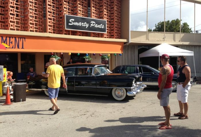 Smarty Pants Bar, a gay travel destination. Men admire classic cars. A fun, welcoming spot for gay men to visit.
