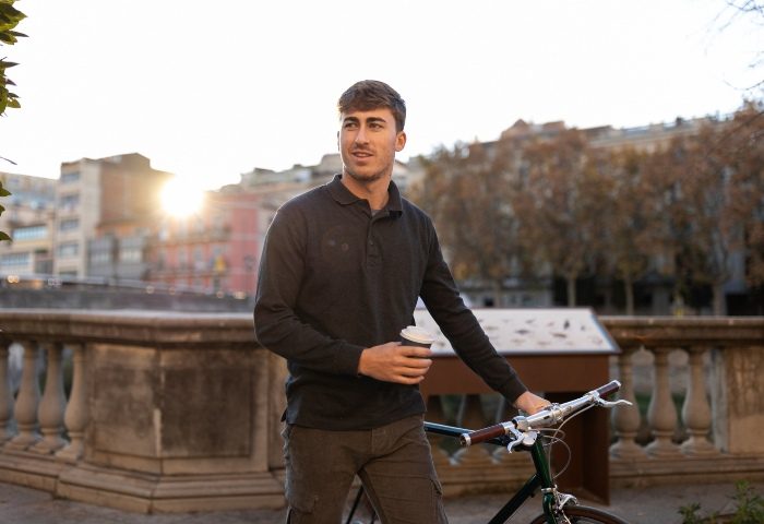 Gay Vienna Travel: A young man with a bicycle and coffee cup in Vienna. Exploring the city, a popular destination for gay travelers.