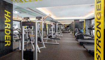 SAii Laguna Phuket gym. Modern fitness center with weight machines and treadmills. Harder, Faster, and Stronger motivational text.