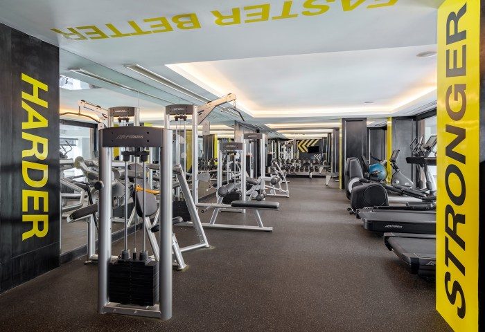 SAii Laguna Phuket gym. Modern fitness center with weight machines and treadmills. Harder, Faster, and Stronger motivational text.