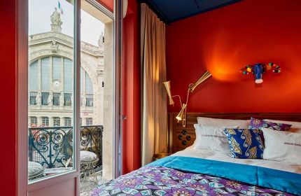 25hours Hotel Terminus Nord, Paris. Colorful room with balcony view. Gay-friendly hotel. Quirky design, vibrant colors, and cozy bed.