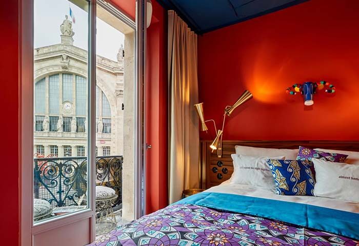 25hours Hotel Terminus Nord, Paris. Colorful room with balcony view. Gay-friendly hotel. Quirky design, vibrant colors, and cozy bed.
