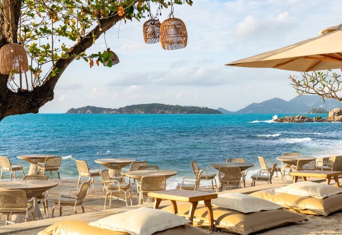 SAii Koh Samui Villas beachside dining. Tables and chairs on the sand, with ocean views. Perfect for gay travel and romantic getaways.