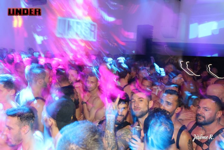 John Dixon's UNDER: Gay men at a dance party. A crowd of shirtless men with harnesses under neon lights. Gay travel advice.