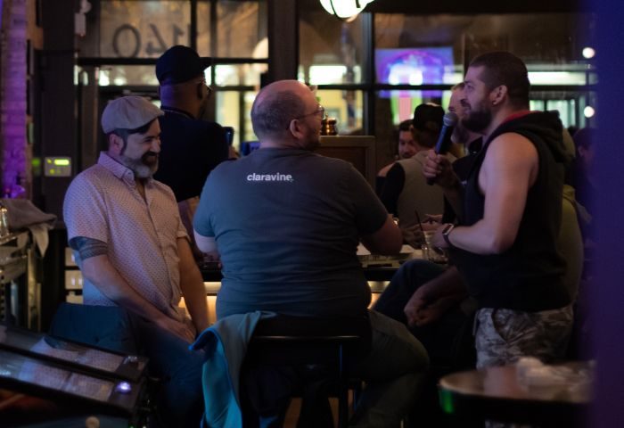 Inside 2Bears Tavern, an Uptown Chicago gay bar. Men are gathered, one with a mic. A popular spot for the gay community.