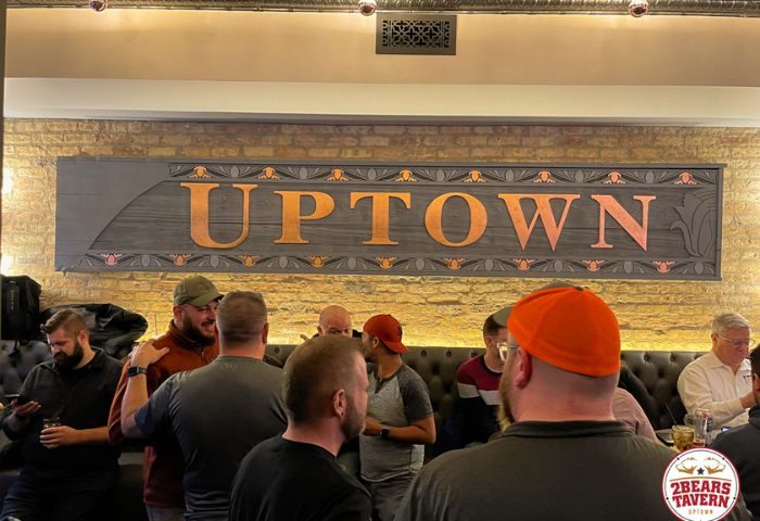 Interior of 2Bears Tavern, an Uptown Chicago gay bar. Group of men socializing under an Uptown sign. Gay travel destination.