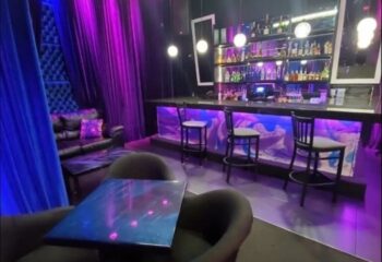 Interior of Boardwalk Bar, a gay bar. Features include a bar, stools, chairs, tables, and purple and blue lighting. Nightlife. 3-11.jpg