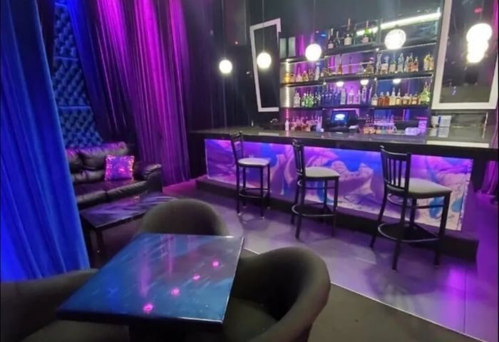Interior of Boardwalk Bar, a gay bar. Features include a bar, stools, chairs, tables, and purple and blue lighting. Nightlife. 3-11.jpg