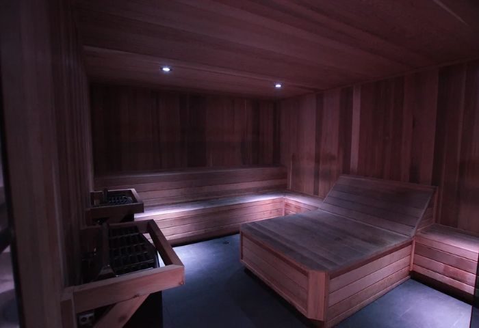 Sauna interior at The Club Fort Lauderdale, a gay men's resort. Features wooden benches, walls, and heater. Relaxation and wellness space.