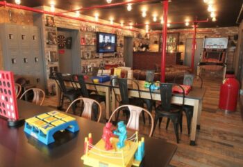 Hotel Gaythering's bar area. Interior of the gay hotel in Miami Beach, Florida. Tables with games for guests, bar, and lounge.