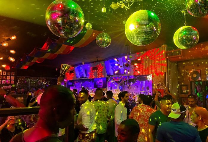 Inside Nathan's Beach Club: A vibrant gay bar scene with disco balls, rainbow decor, and a diverse crowd enjoying the lively atmosphere.