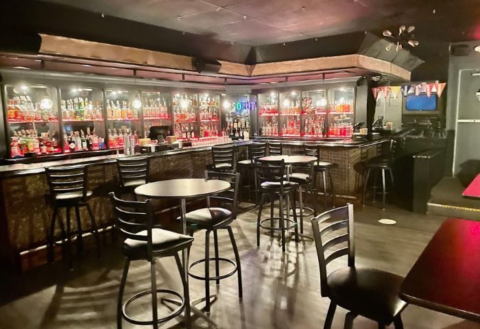 Interior of The Eagle Wilton Manors bar. Bottles on shelves behind the bar, tables and chairs in the foreground. Gay bar in Wilton Manors.