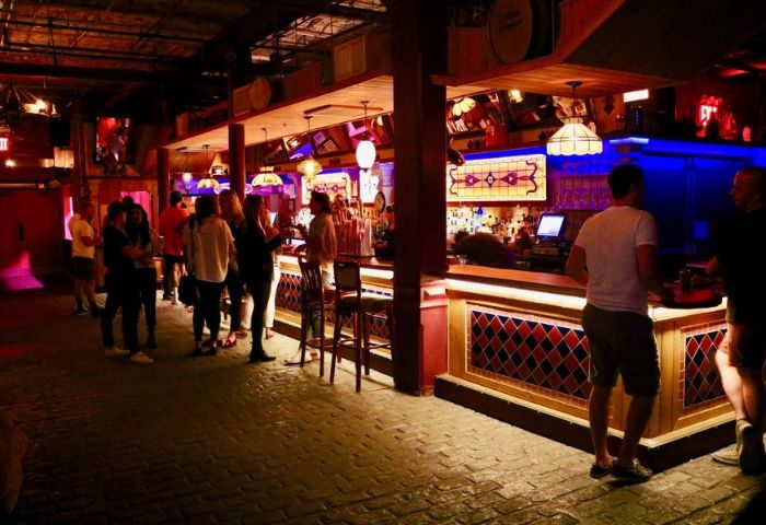 Gay bar in New York: 3 Dollar Bill interior. People at the bar, warm lighting, brick floor. Gay travel advice, nightlife, social scene.